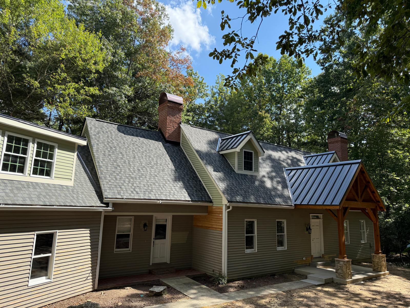 Custom home with shingle roofing and metal accent porch roof